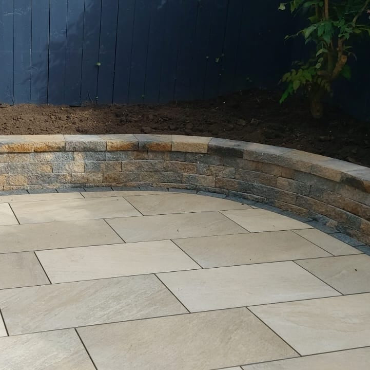 Paved patio area with stone tiles in front of a garden wall.