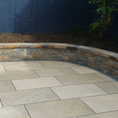 Paved patio area with stone tiles in front of a garden wall.