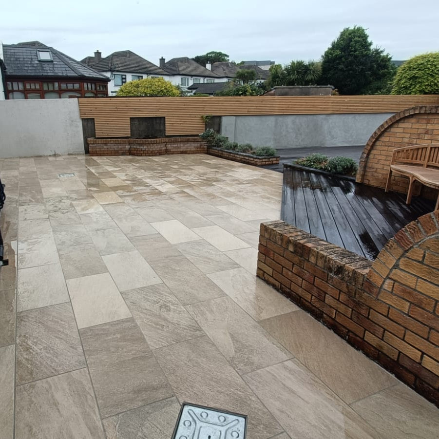 Terrace with outdoor porcelain paving, outdoor furniture, and surrounding buildings. Paving is Gold Quartz Diva Range Porcelain Paving Tiles. 