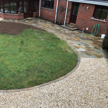Red brick house with patio area, grass and pathway in Gold Shingle Stone Chipping. 