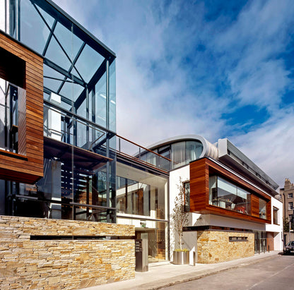 Modern building completed with Gold Donegal Quartzite Random Rubble walling stone and glass design against a blue sky.