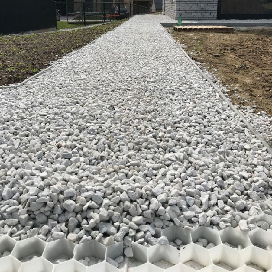 Decorative aggregate spread on top of gravel girds on a pathway leading to a modern house.  
