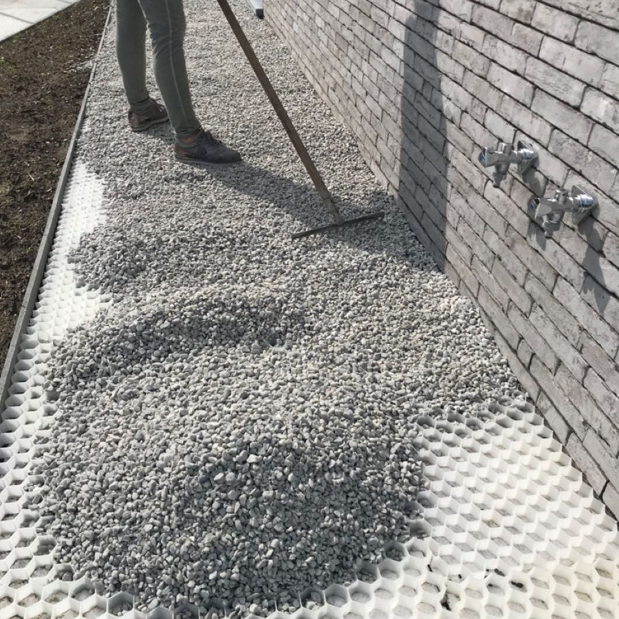 Decorative aggregates being spread over gravel grids with rake. 