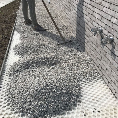 Decorative aggregates being spread over gravel grids with rake. 