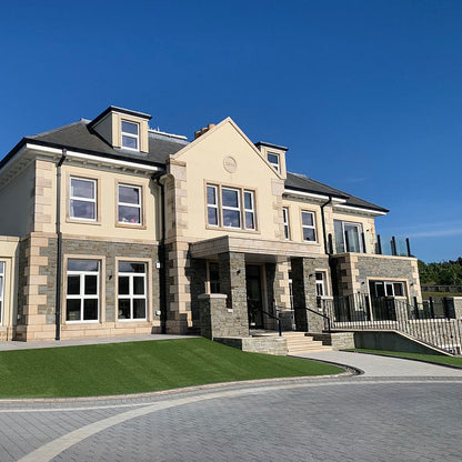 Two storey house with grey sandstone machined walling stone on the ground floor walls. 
