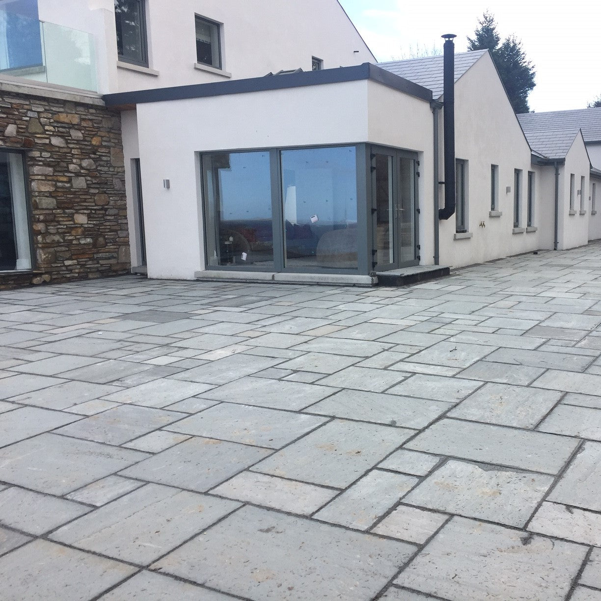 Large modern house with patio area completed using Grey Sandstone Patio Packs. 