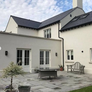 Modern house exterior with patio area finished in Grey Sandstone paving. 