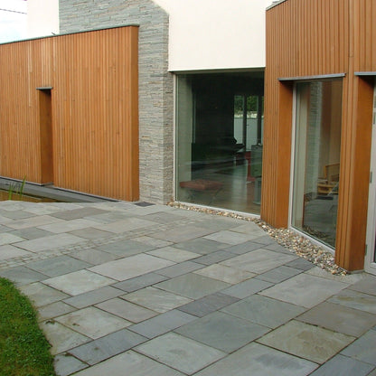 Modern house with Grey Sandstone Paving and wooden wall cladding. 