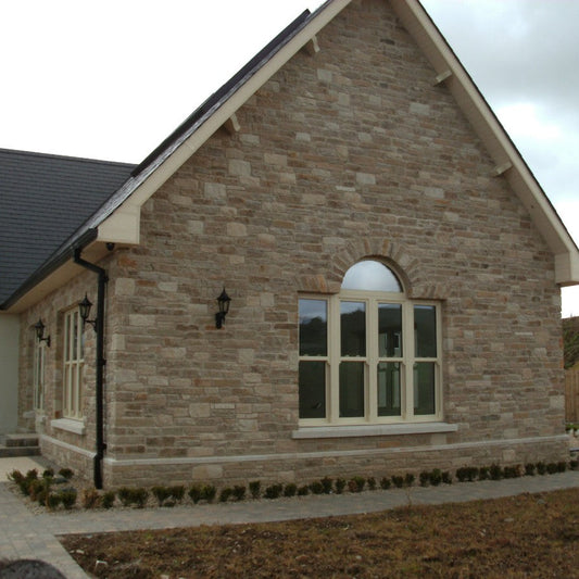 Stone façade featuring Grit Sandstone Machined and a large cream arched window.