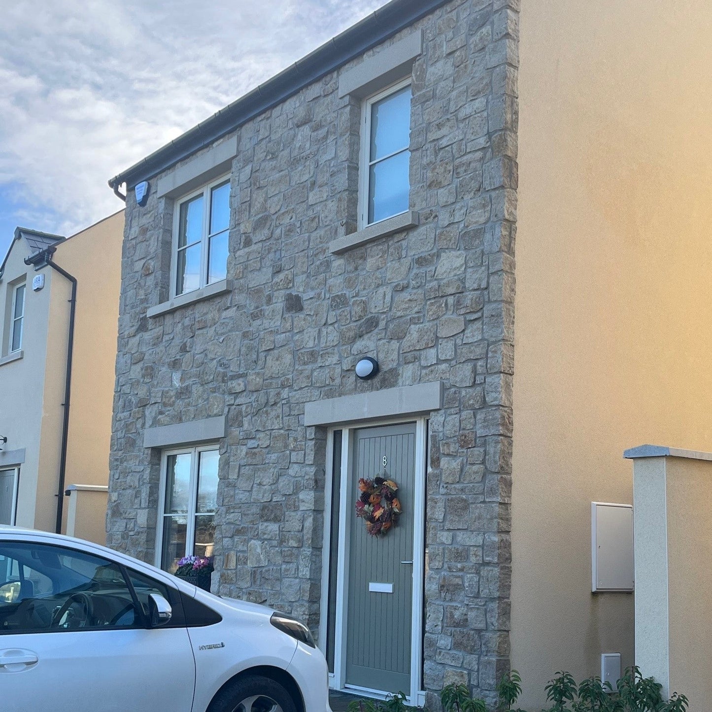 An estate house with stone feature wall finished in Grit Sandstone Stoneer Cladding.