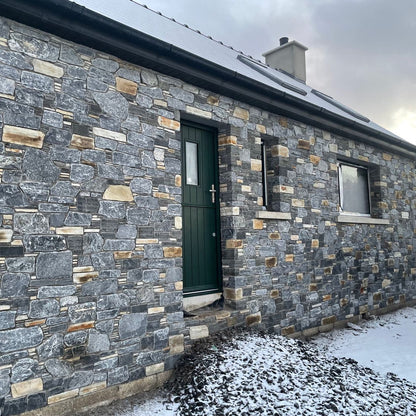 Stone house with a green door completed in highland blend tumbled walling stone. 