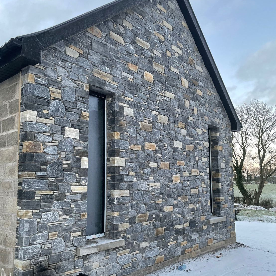 Stone house with two long windows completed in highland blend tumbled walling stone. 
