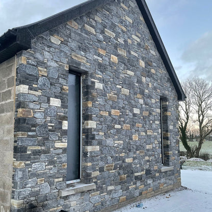 Stone house with two long windows completed in highland blend tumbled walling stone. 