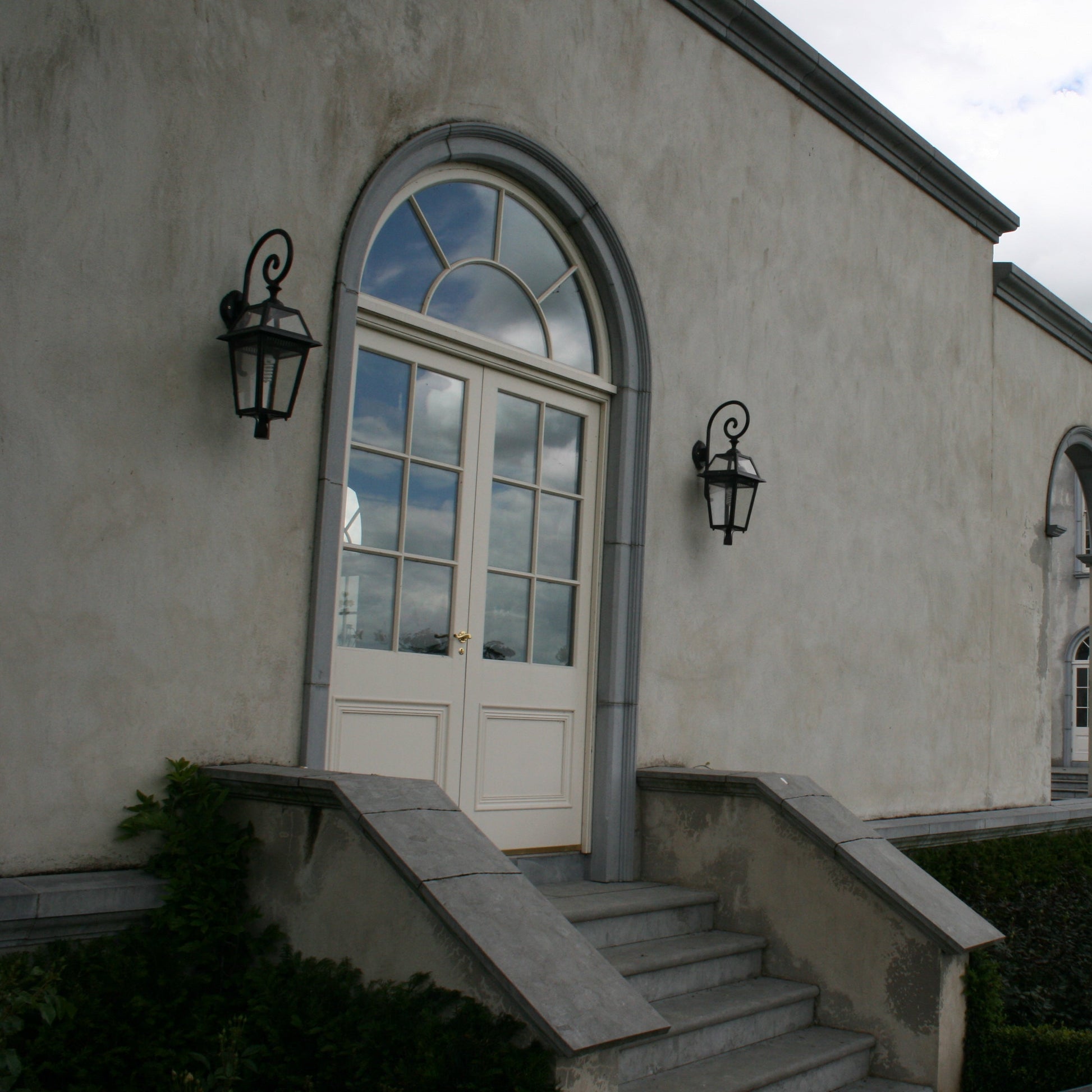 Stately building with arched windows completed with bespoke blue limestone surrounds and steps leading up to a door.