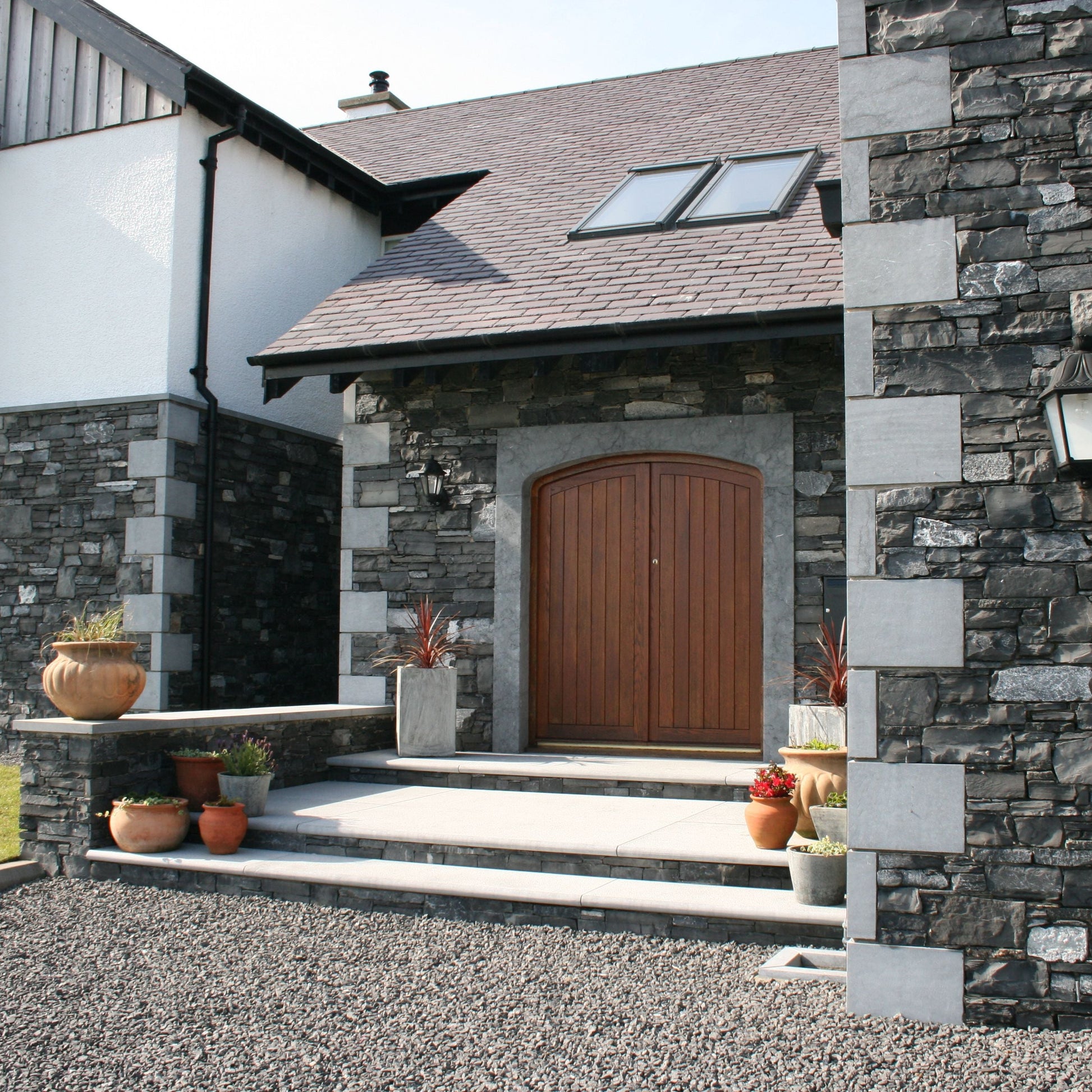 Stone house exterior with a wooden door and bespoke Blue Limestone Door Surround and Quoins. 