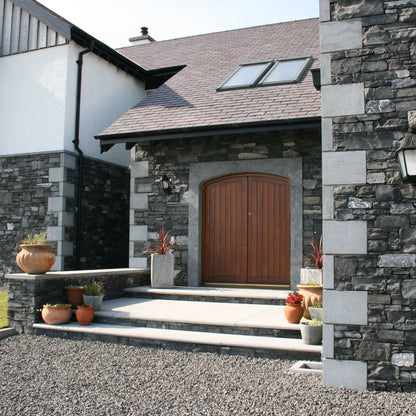 Stone house exterior with a wooden door and bespoke Blue Limestone Door Surround and Quoins. 