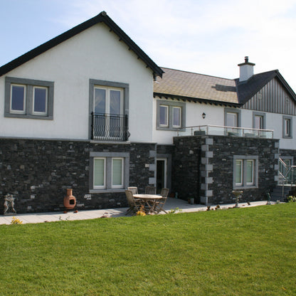 Two-story house with a stone façade and bespoke Blue Limestone Door & Window Surrounds. 