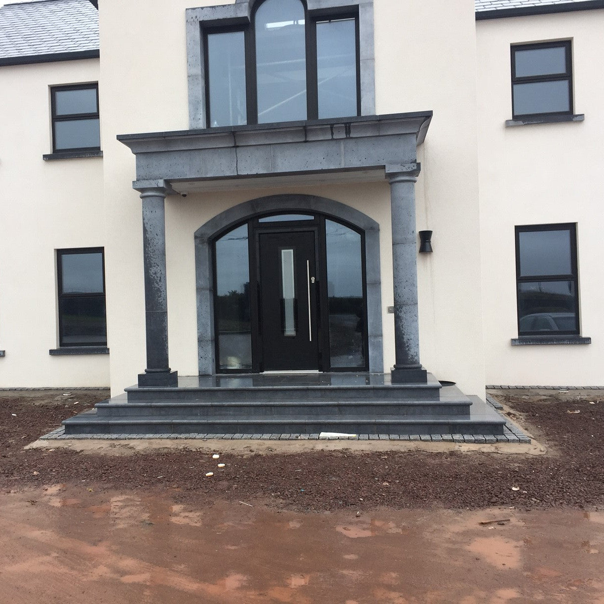 Modern house with a limestone portico and black door and windows