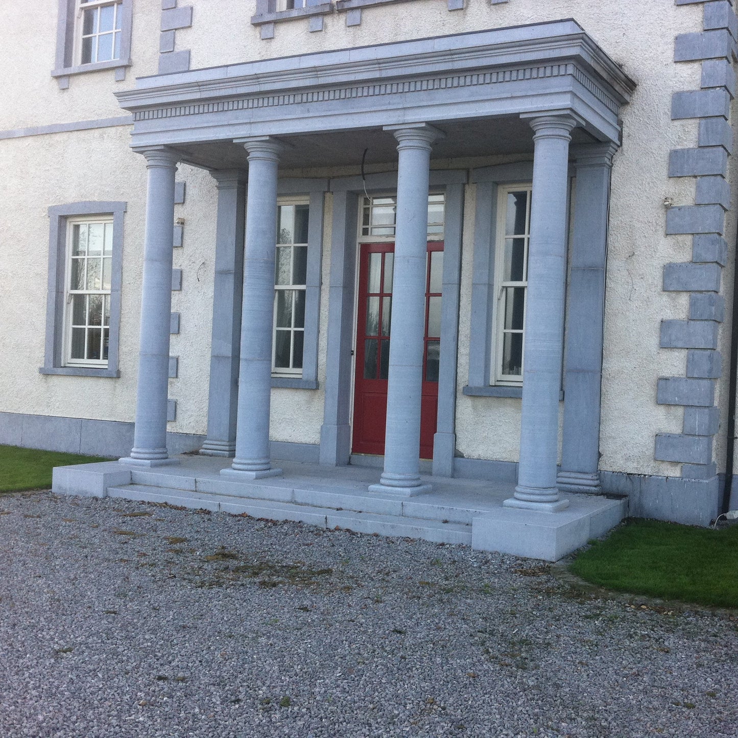 Stately home with classical style Limestone portico and red door. 