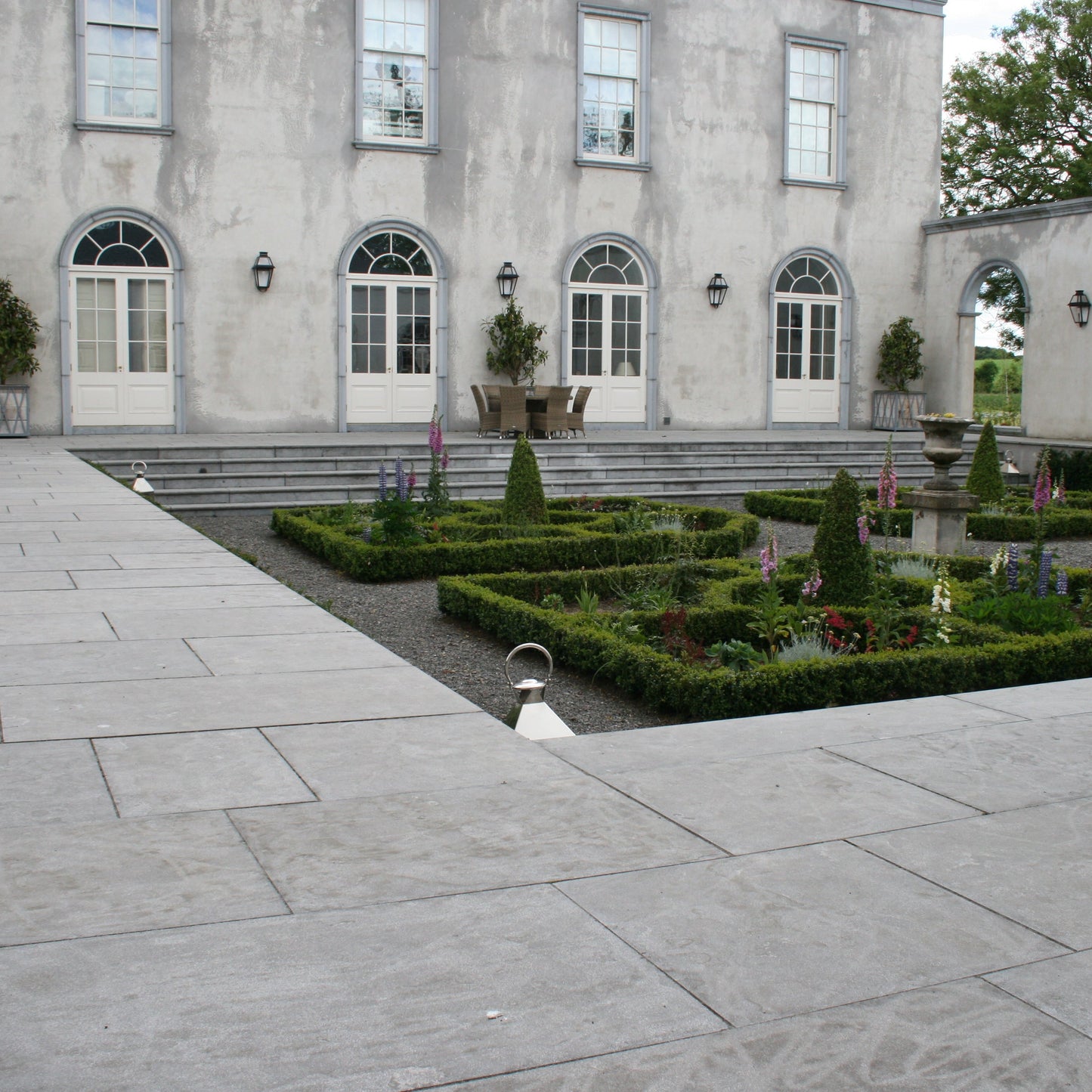 Large stone building with a well-maintained garden in front. Building features bespoke Blue Limestone Window & Door Surrounds. 