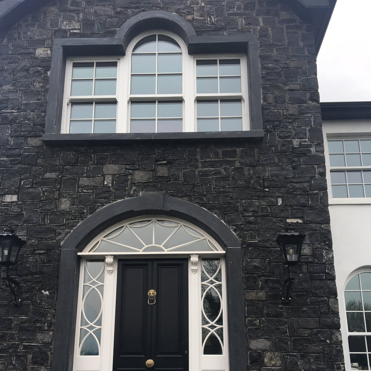 Dark stone building with a limestone window and door surround. 