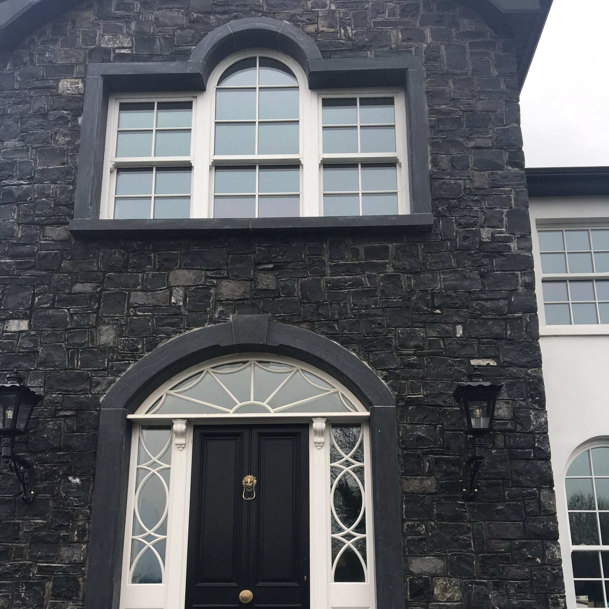 Dark stone building with a limestone window and door surround. 