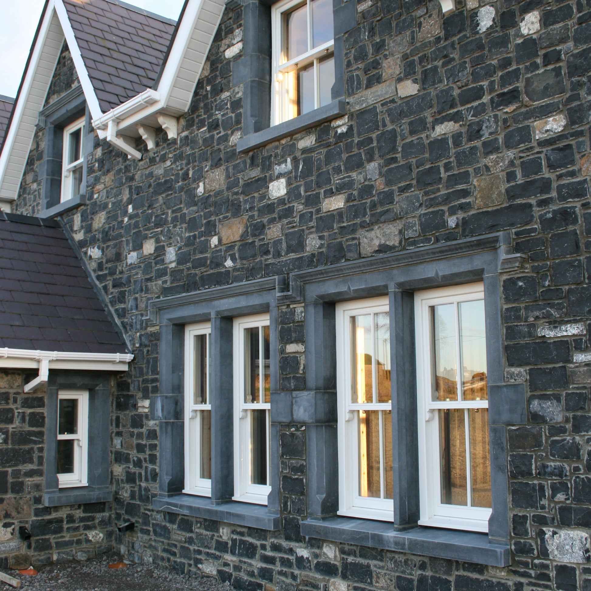 Stone building with bespoke blue limestone window surrounds. 