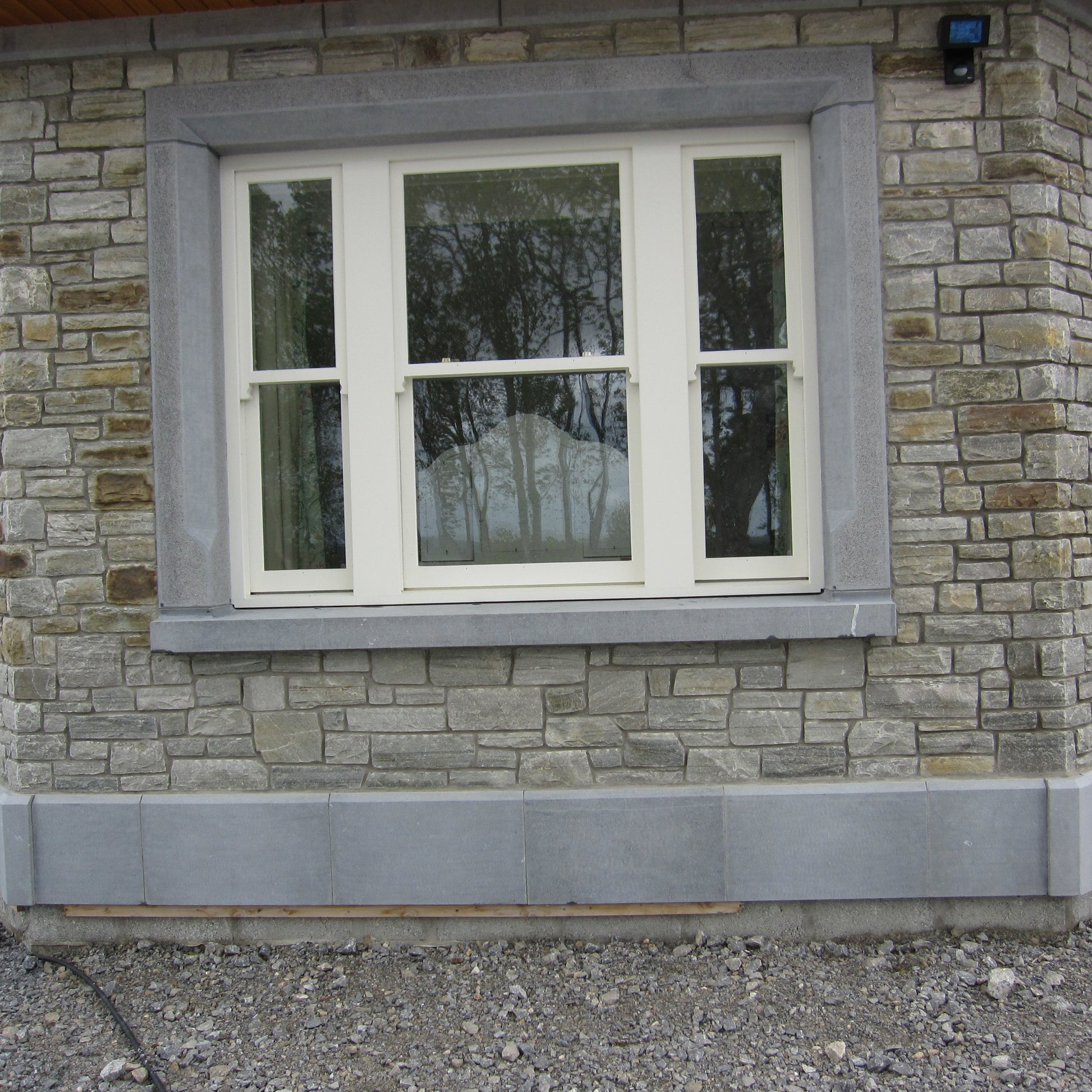 Stone building with a window and limestone window surround and plinth. 
