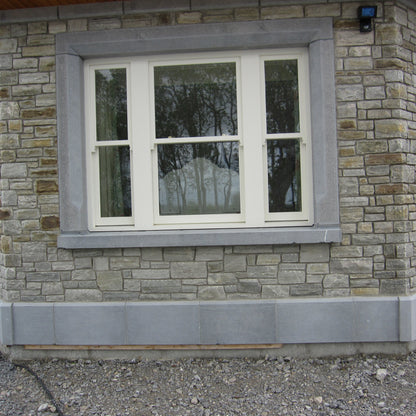 Stone building with a window and limestone window surround and plinth. 