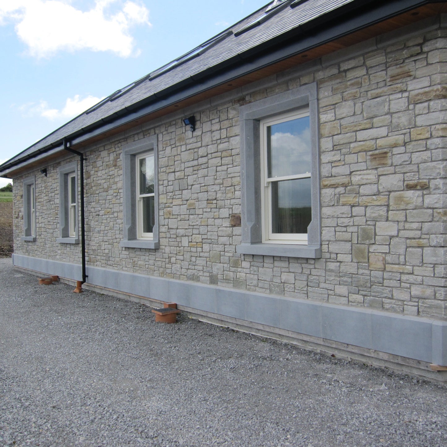 Stone building with bespoke Blue Limestone Window Surrounds and Plinth. 