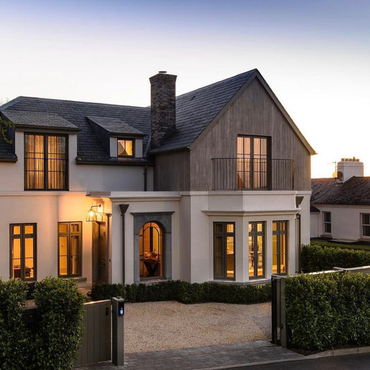 A two-story residential building with door and window surrounds made of bespoke limestone, displayed during twilight.