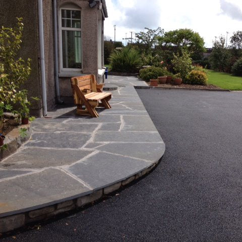 Driveway leading to a house with a stone pathway in Liscannor Slate Crazy Paving and garden area.