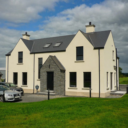Two storey white house with a grey stone porch in Liscannor Slate building stone.