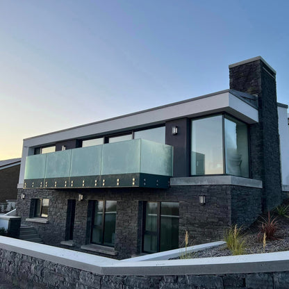 Modern stone clad house with glass balustrade on a clear day. Stonework is Liscannor Slate Stoneer Cladding. 