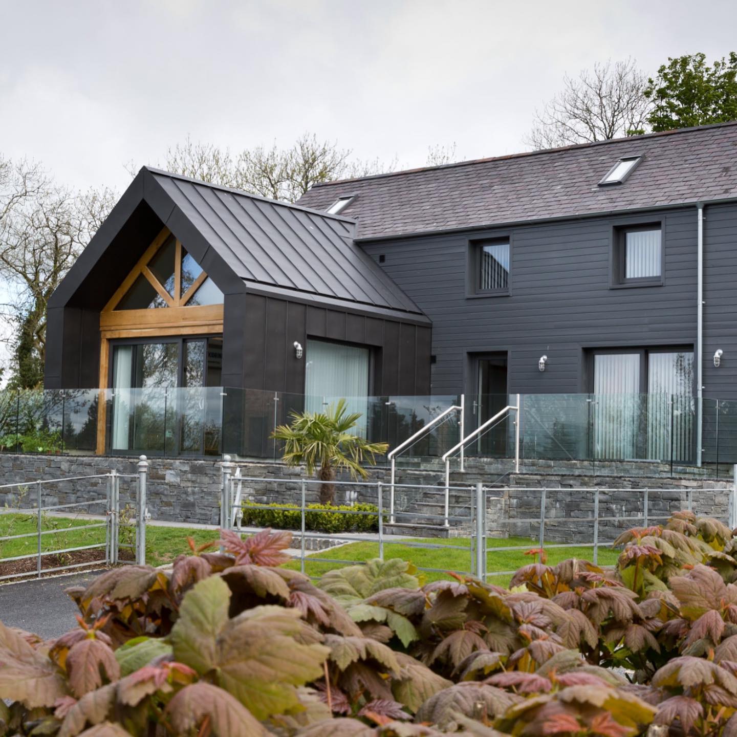 Raised patio wall with glass balustrade and cladded in Liscannor Slate Stoneer. 