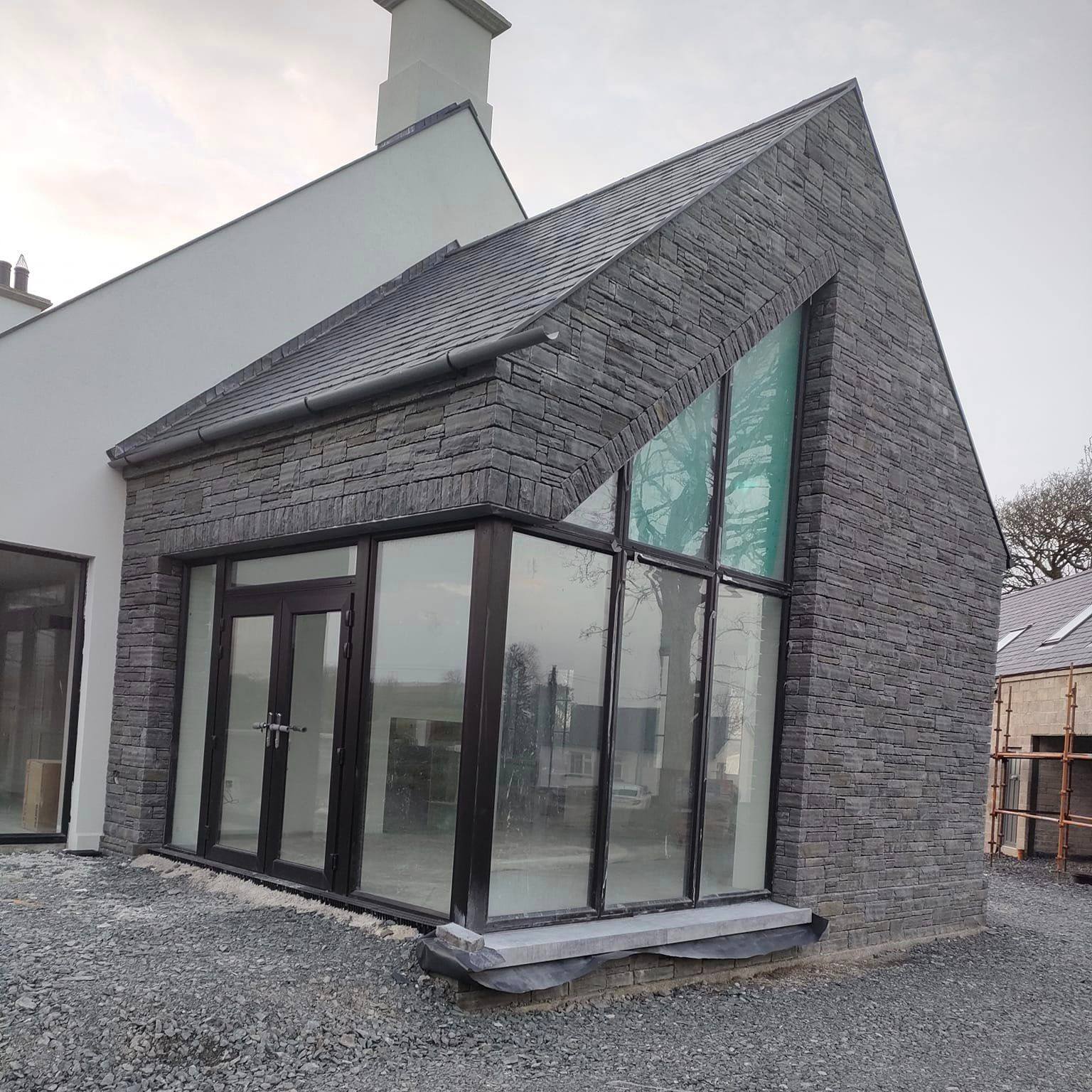 Modern new build with large windows. Walls are cladded in Liscannor Slate Stoneer Cladding. 