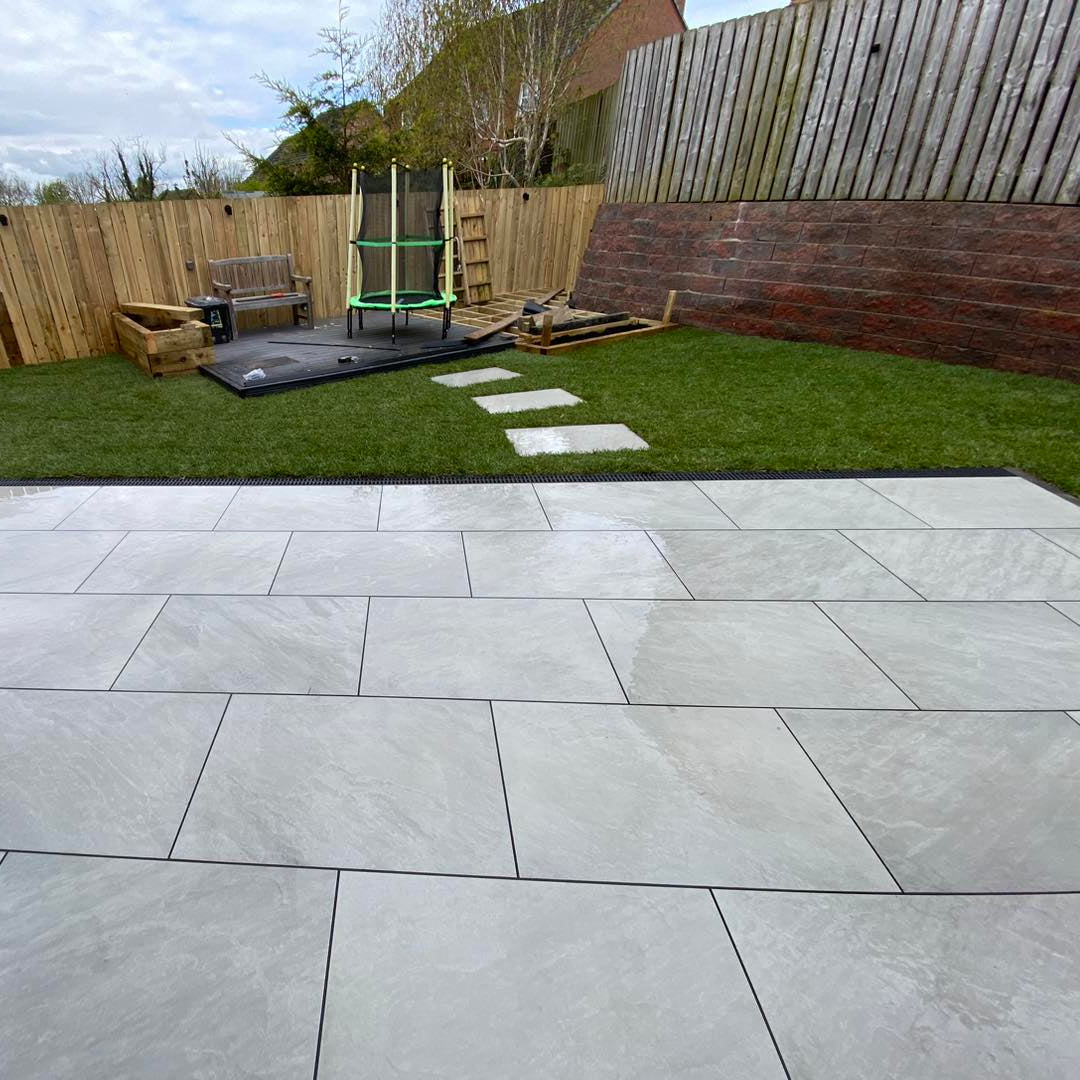 Patio area with stepping stones leading to trampoline. Paving is Mercury Grey Jewel Range Porcelain Paving. 
