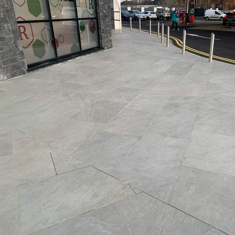 An outdoor installation of Mercury Grey porcelain paving tiles in a garden setting, with a grey colour.