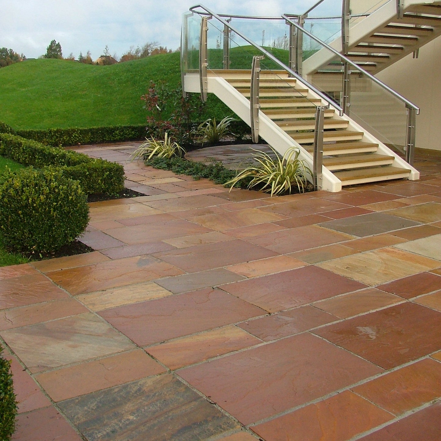 External staircase leading down to patio area featuring Modak Sandstone Paving. 