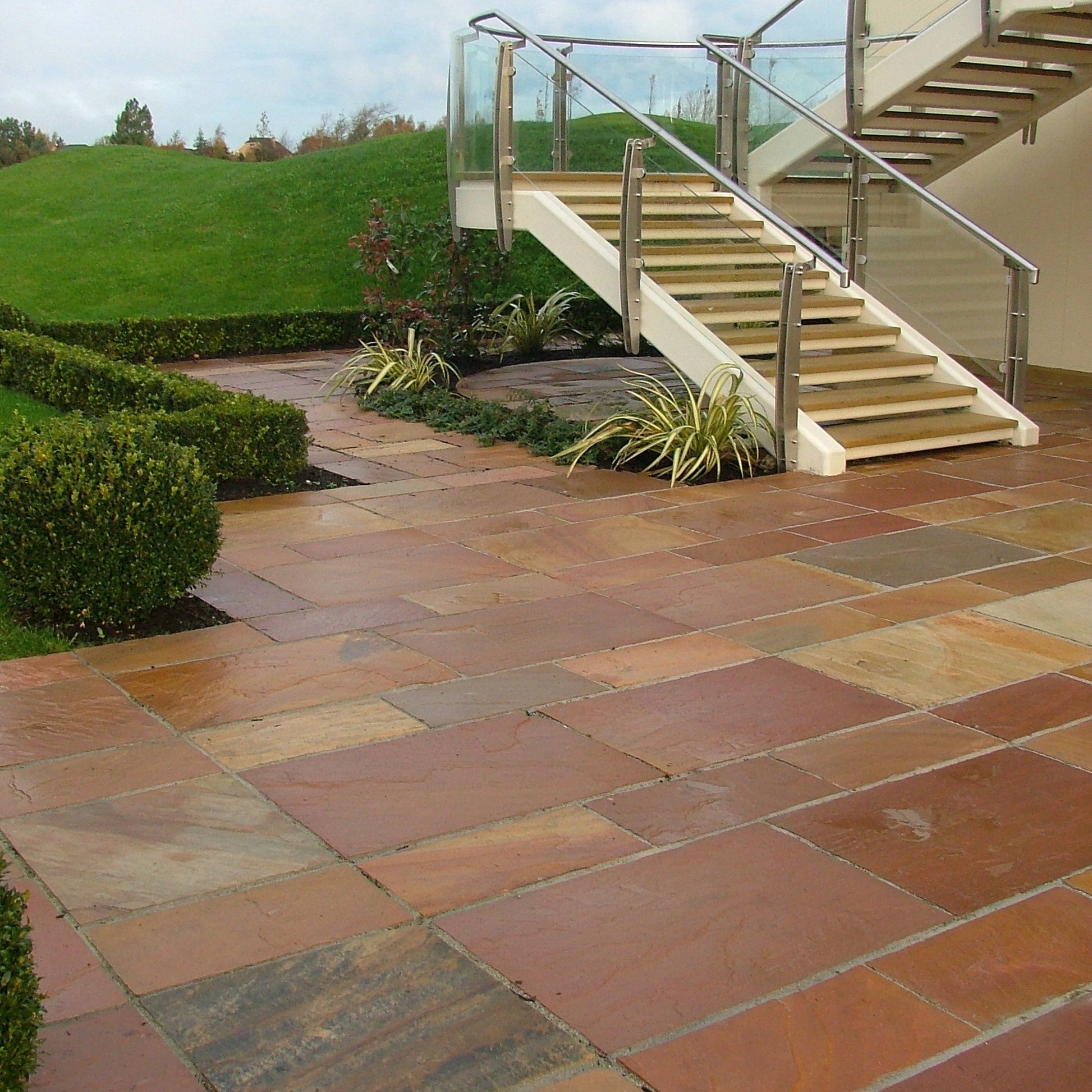 External staircase leading down to patio area featuring Modak Sandstone Paving. 