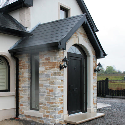 House exterior with stone façade and black door with bespoke sandstone surround and step. 
