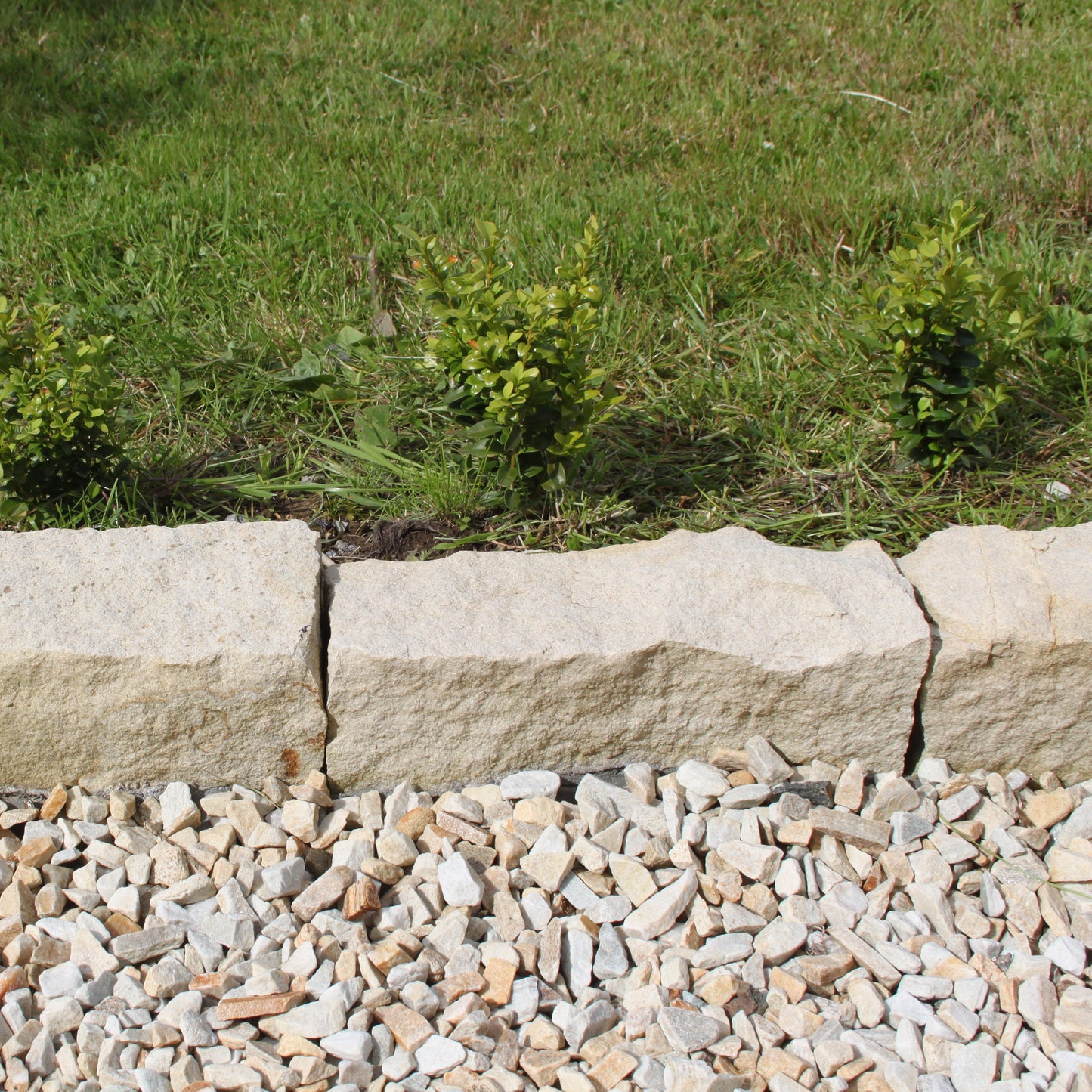 Close up of Mountcharles Sandstone Kerbs installed between a garden and stone chipping pathway. 
