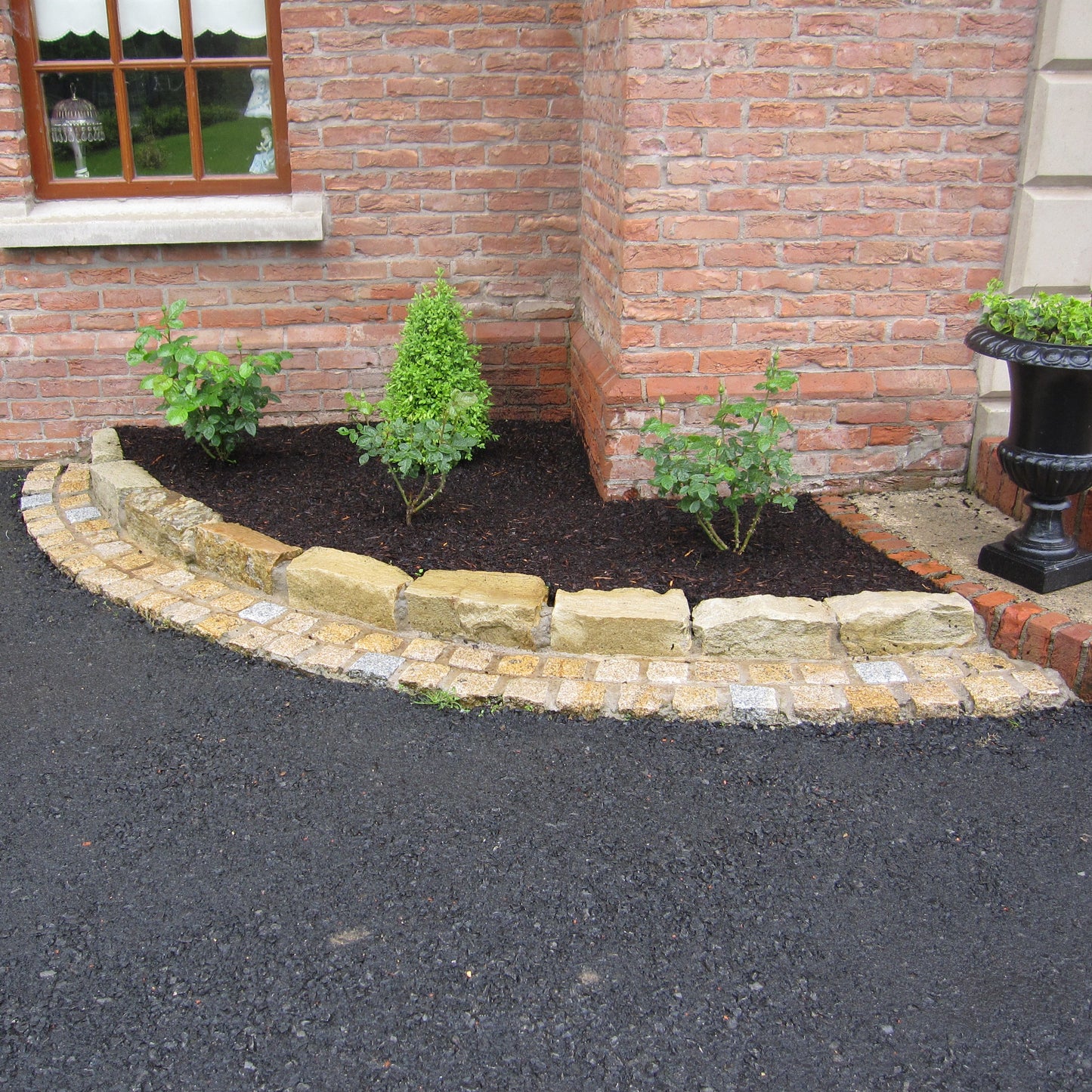 Red brick house with planting surrounded by Mountcharles Sandstone Kerbing. 
