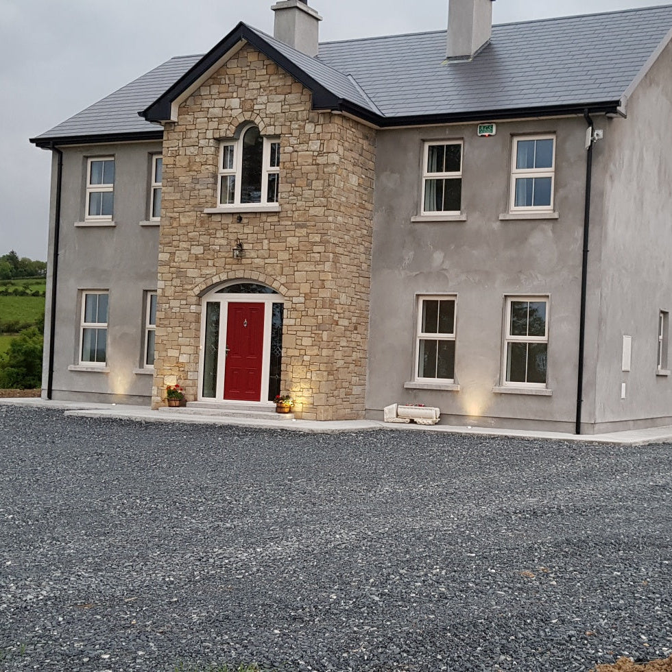 Two-story house with a driveway and garage in a rural setting. Stone is Mountcharles Sandstone Machined. 