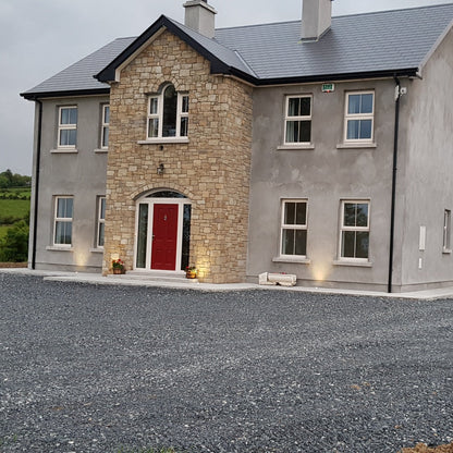 Two-story house with a driveway and garage in a rural setting. Stone is Mountcharles Sandstone Machined. 