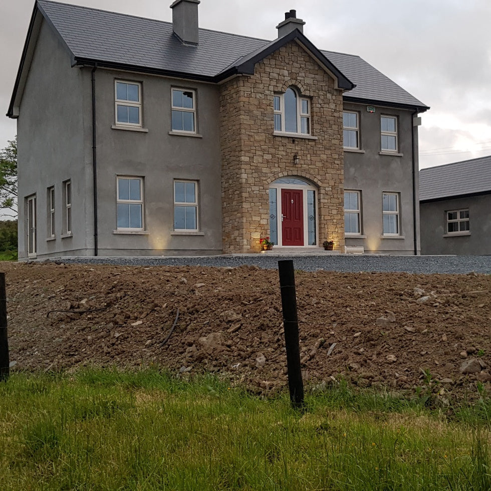 Two-story house with a red door in a rural setting. Stone is Mountcharles Sandstone Machined.  