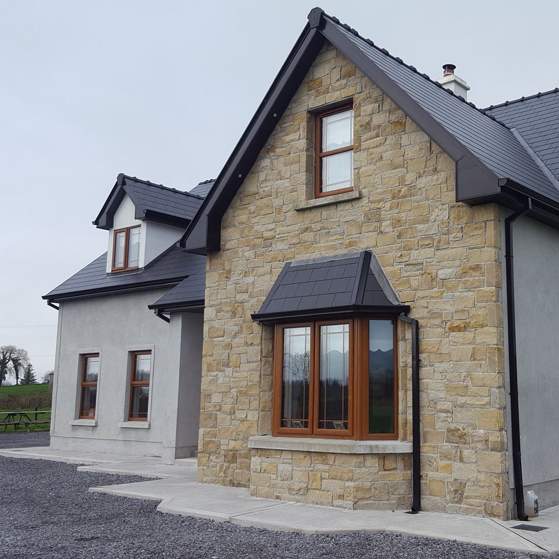 Story and a half house with stone façade in Mountcharles Sandstone Machined. 
