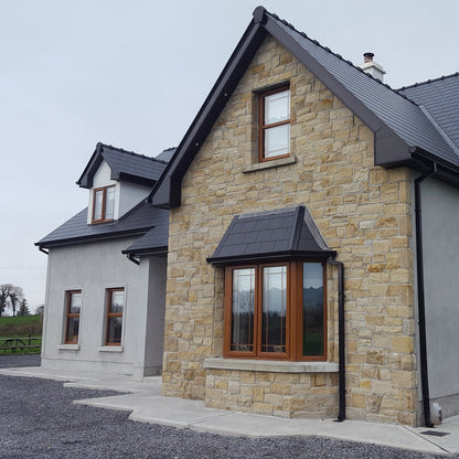 Story and a half house with stone façade in Mountcharles Sandstone Machined. 
