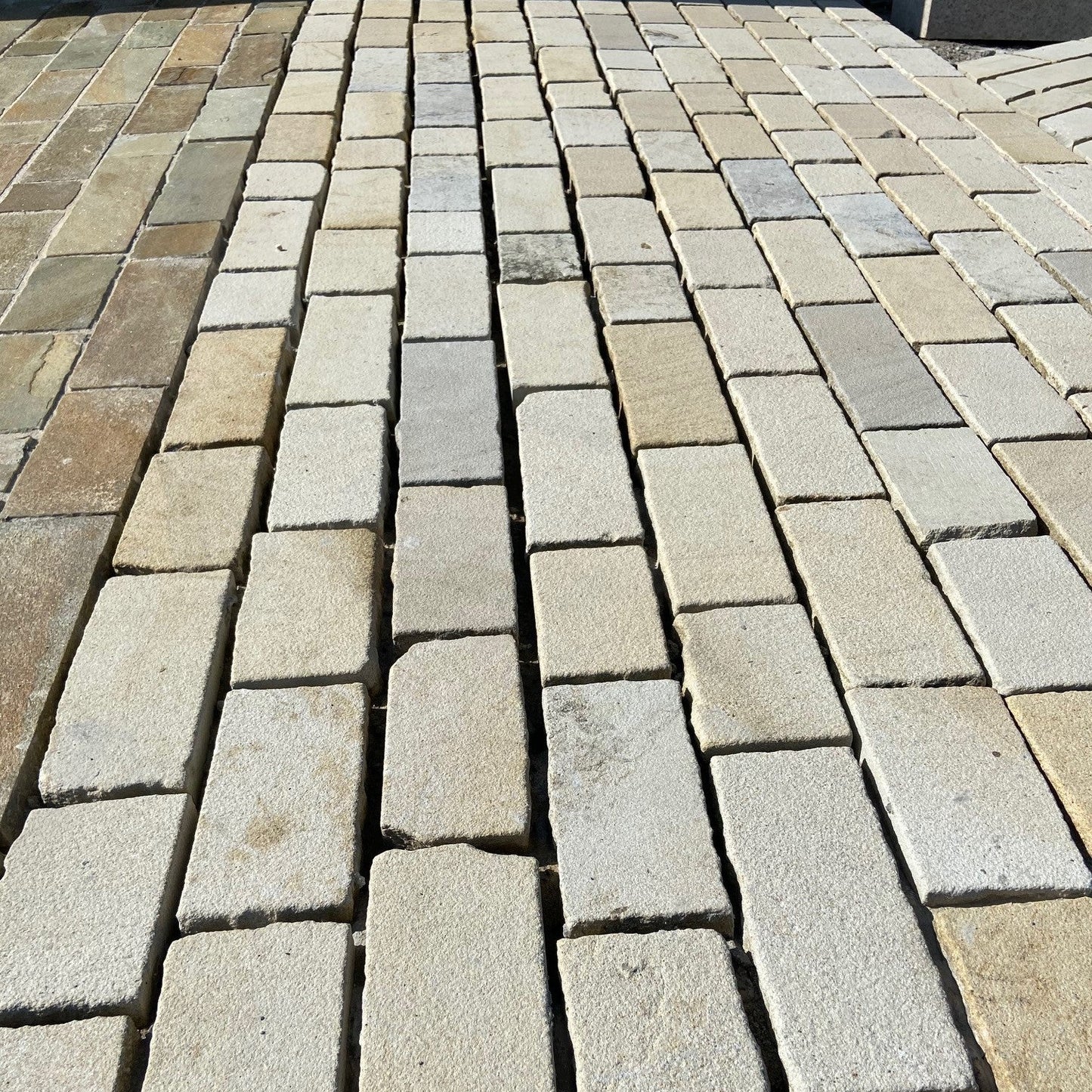 Close up of Mountcharles Sandstone Paving Setts in RL x 100mm size un-grouted to show natural split edge and blasted surface finish. 