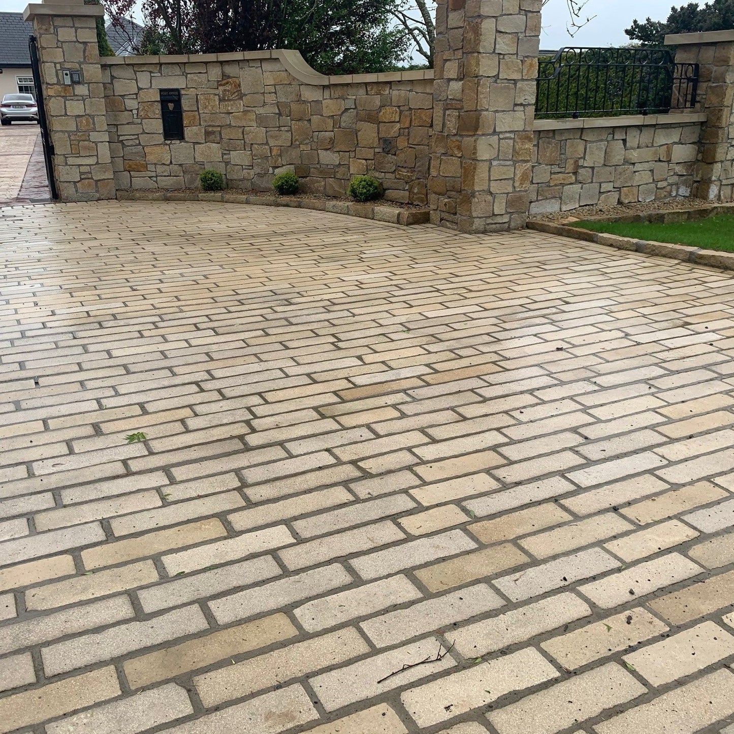 Cobble driveway featuring Mountcharles Sandstone Paving Setts leading to a stone wall with a house in the background